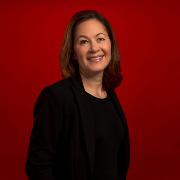 Professional portrait of Stacey Bernards, captured against a bold red background.