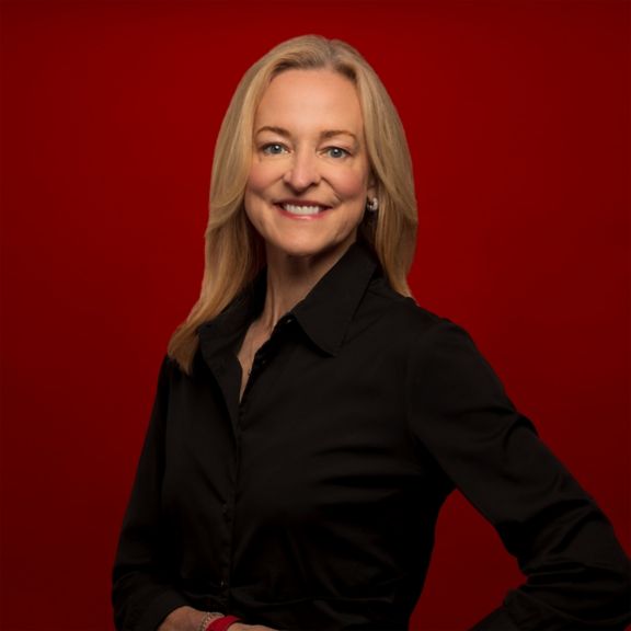 Professional portrait of Stacey Jones, captured against a bold red background.