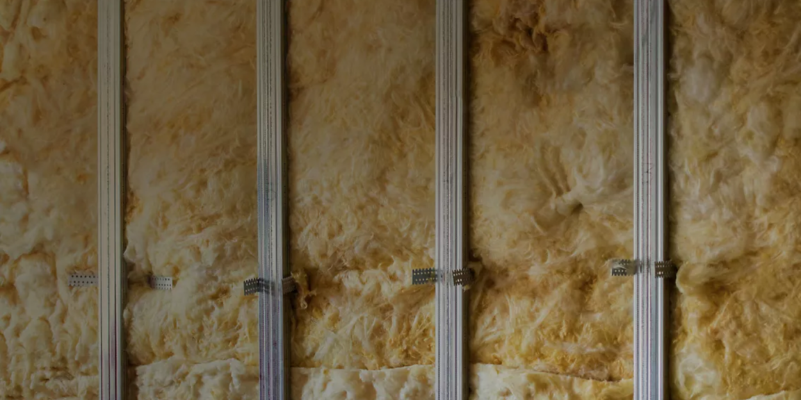 Close-up of fiberglass insulation in wall framing, highlighting thermal efficiency, energy savings, and modern building materials.