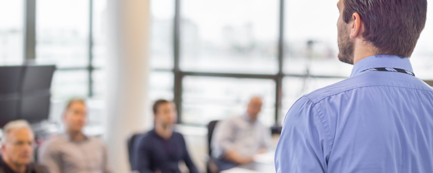 Business man making a presentation at office. Business executive delivering a presentation to his colleagues during meeting or in-house business training, explaining business plans to his employees. 