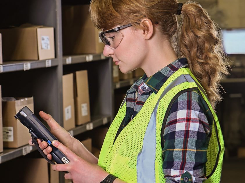 woman using a mobile device in front of shelves