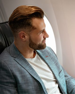 Business traveler seated by an airplane window with a laptop, representing professional mobility and opportunity.