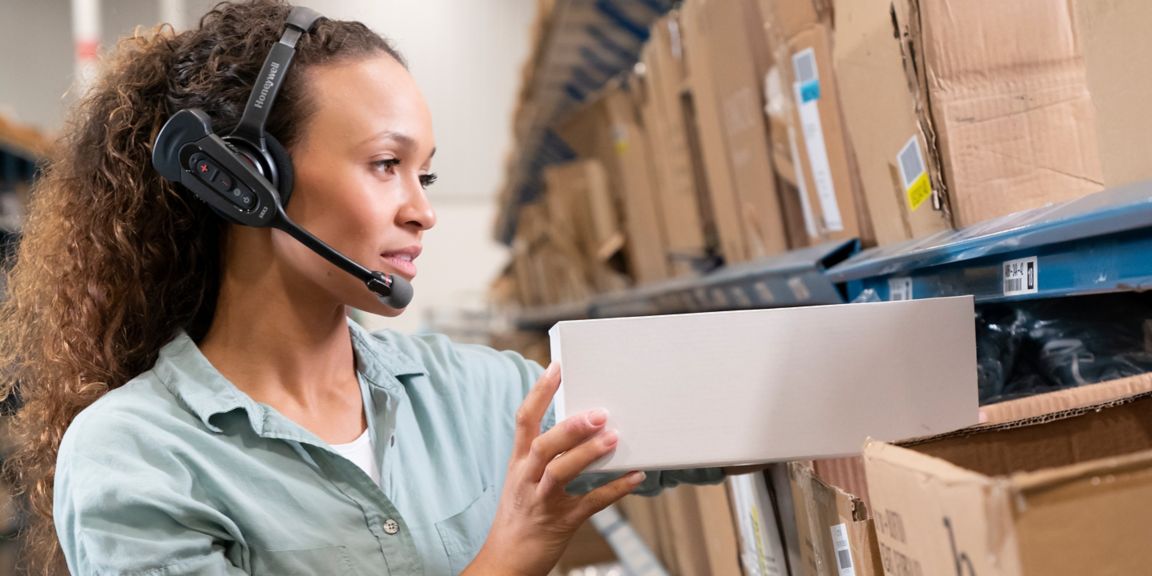woman wearing headset, putting a box on a shelf