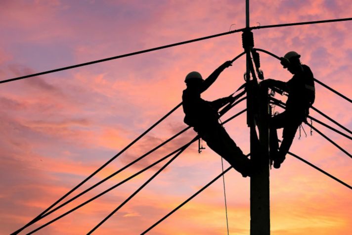 Electrician worker climbing electric power pole to repair the damaged power cable line problems after the storm.