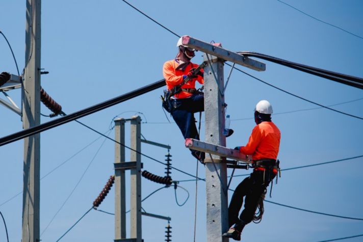 Electricians are climbing on electric poles to install and repair power lines.