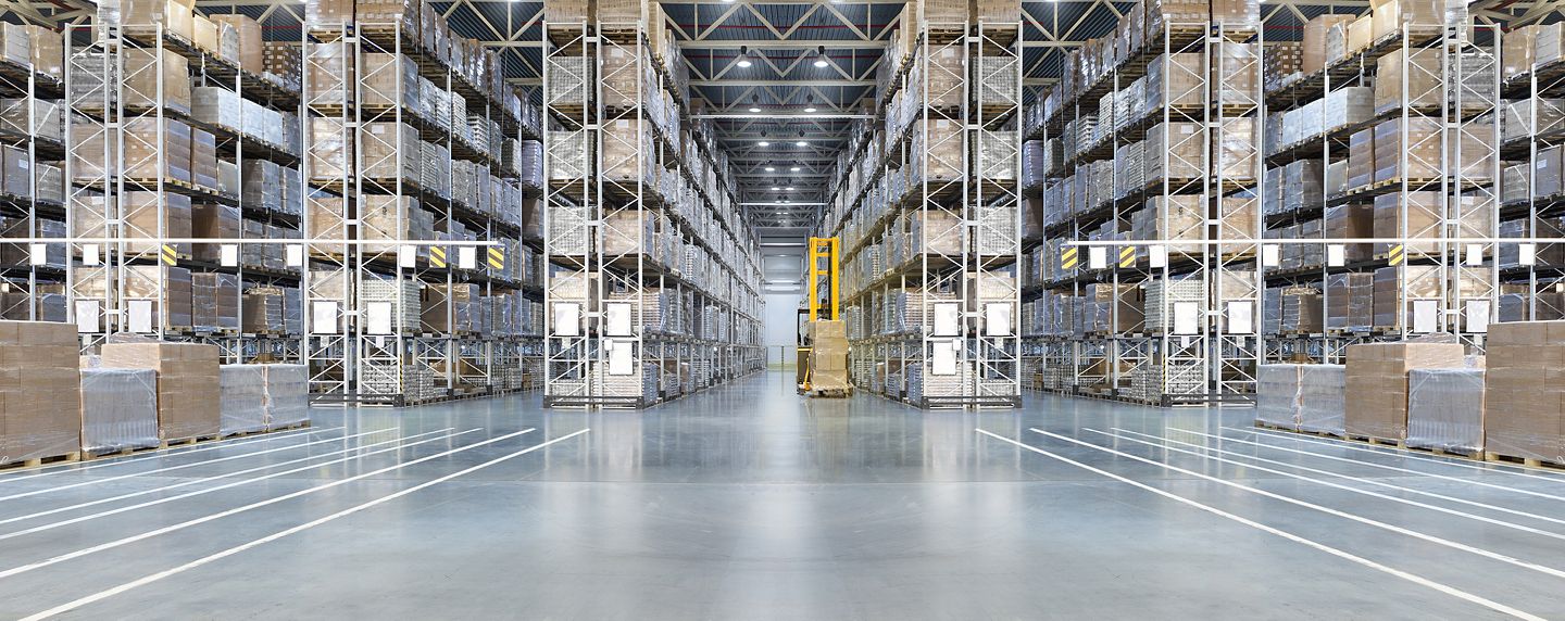 Huge distribution warehouse with high shelves and loaders. Bottom view.