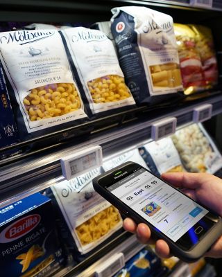 hand using a Honeywell mobile device in front of a shelf