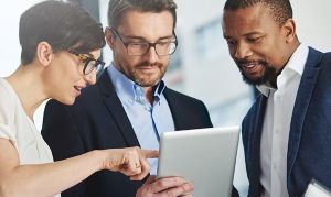 three people looking at a tablet 