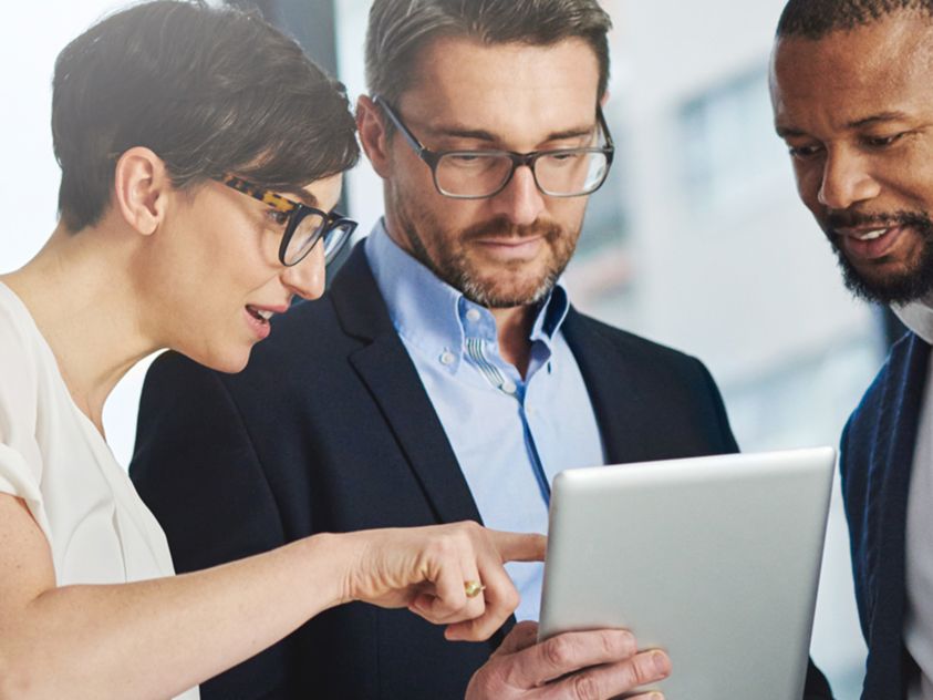 three people looking at a tablet 
