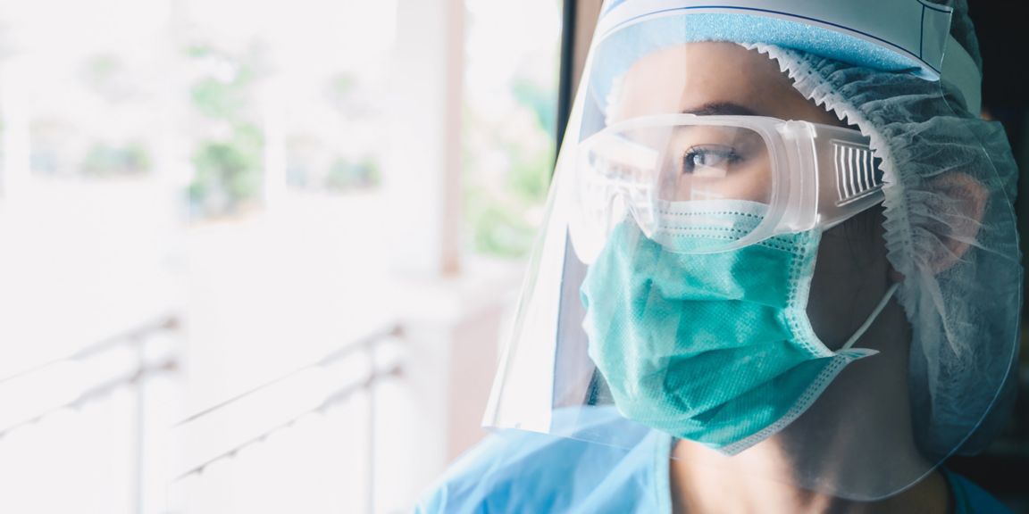 nurse wearing protective equipment looking through the window 