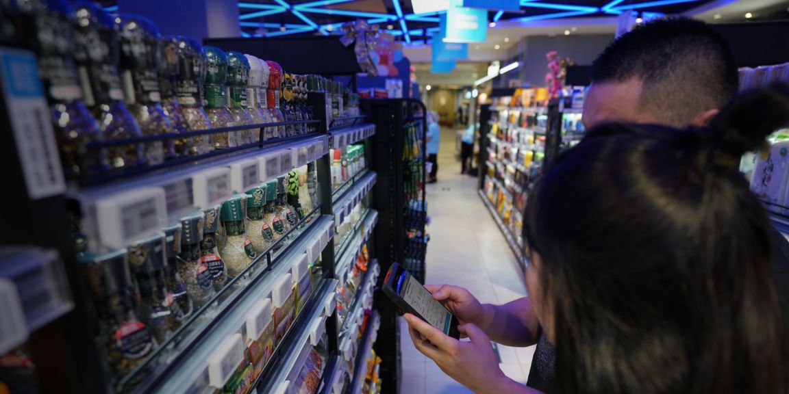 people using a mobile device in front a shelf