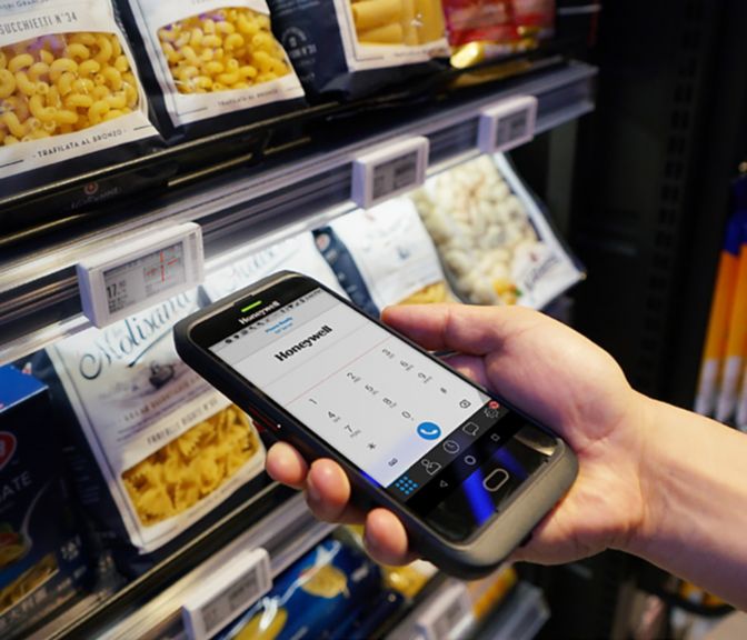 man using a Honeywell device in front of a shelf