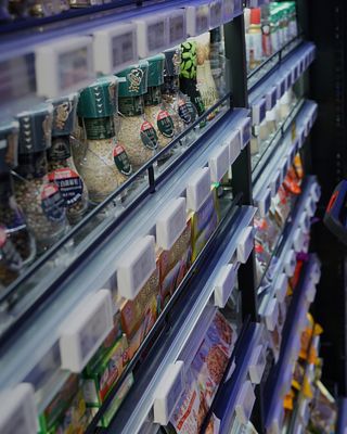 people using a mobile device in front of a shelf with groceries