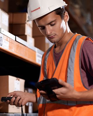 worker between shelves holding a mobile device