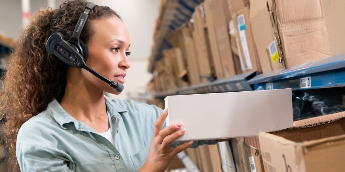 woman wearing headset and putting a box on a shelf