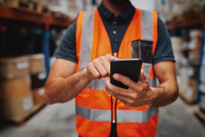 Man hands using smartphone in factory warehouse