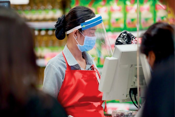retail checkout assistant wearing safety equipment