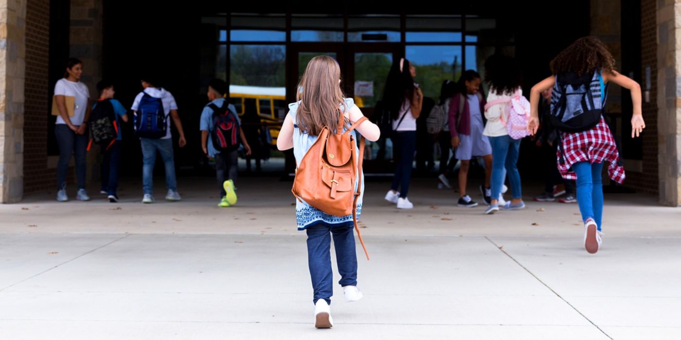 Childrens with bags are running into school