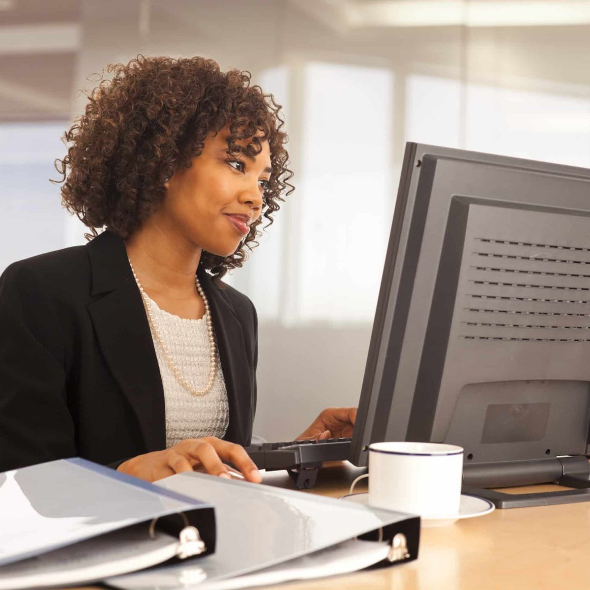 Young businesswoman using computer at desk indoors office building