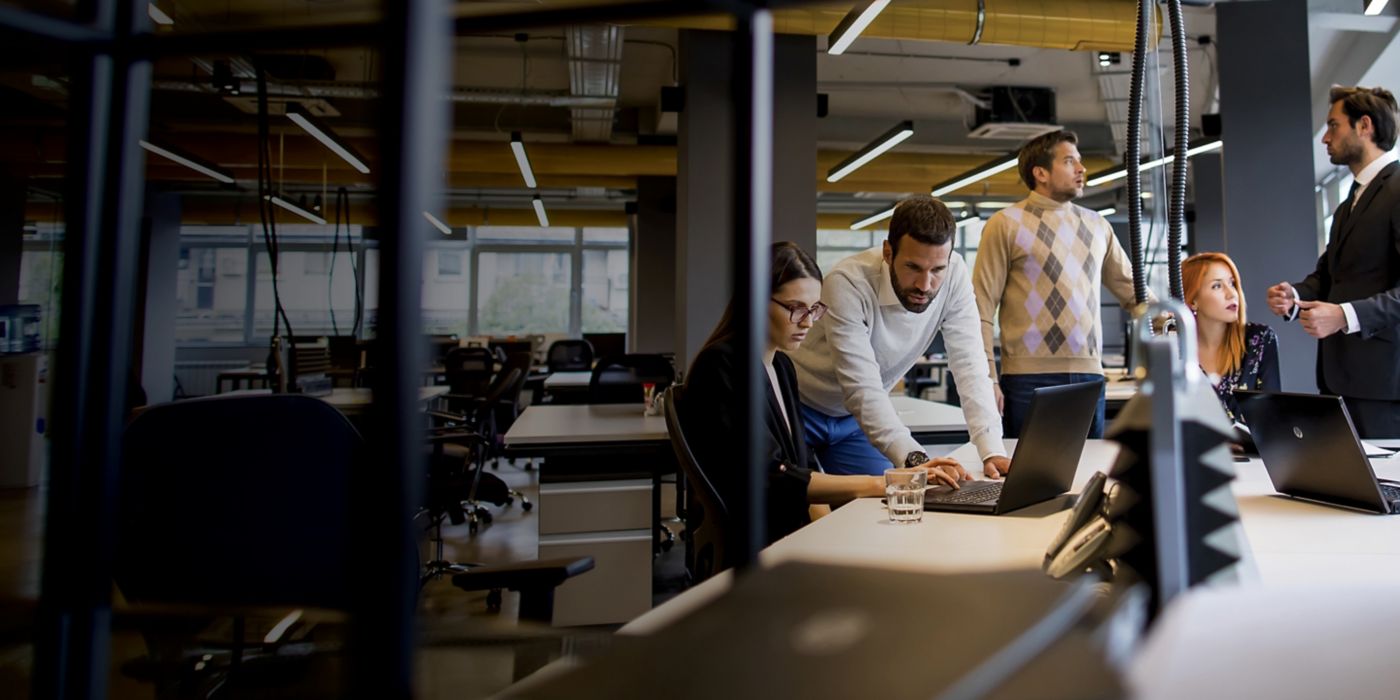 Workers huddled together at an office desk.