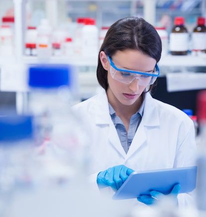 Chemist wearing safety glasses and using tablet pc in lab