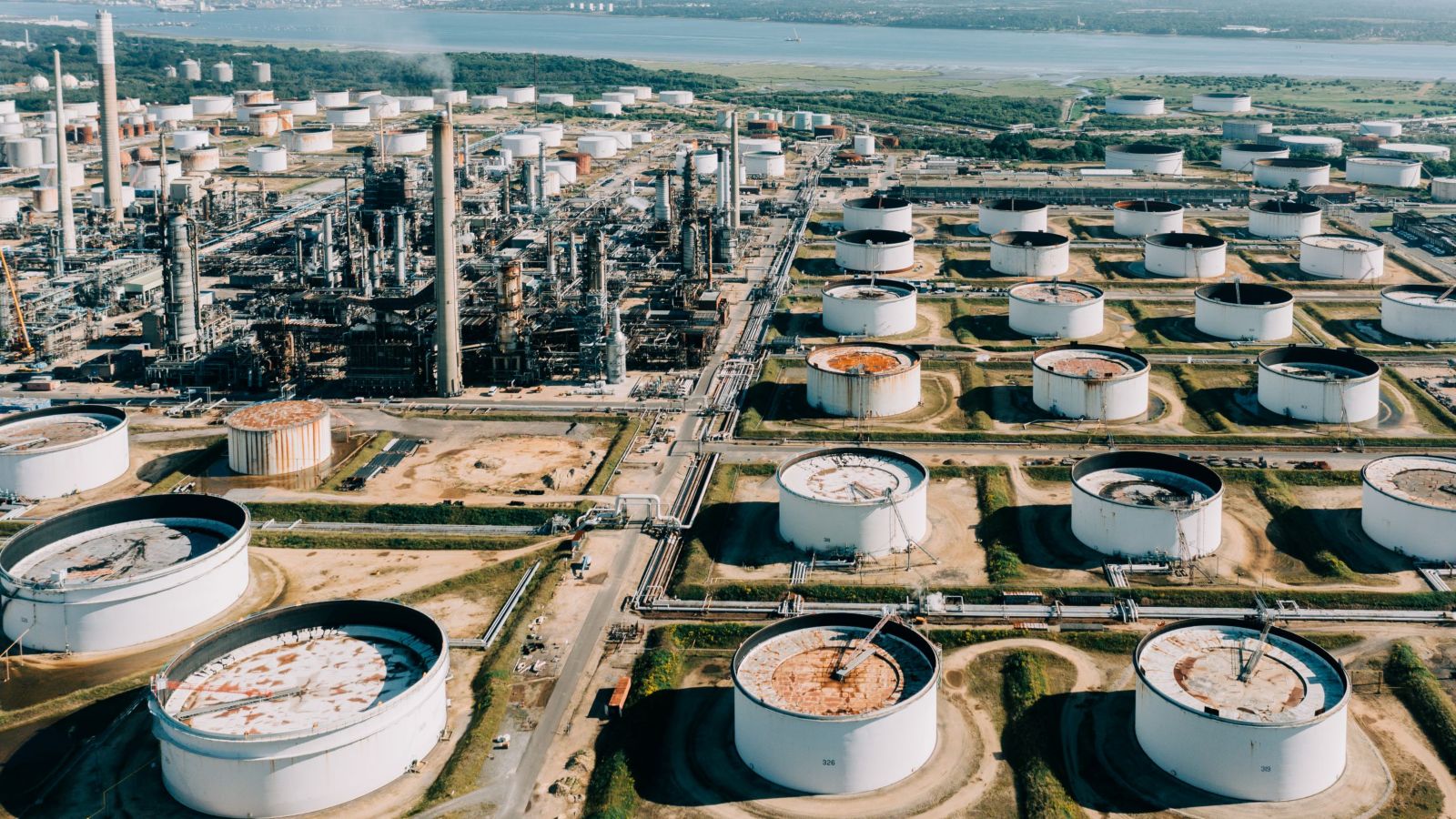 A vast industrial complex featuring numerous storage tanks and refineries, set against a scenic landscape.