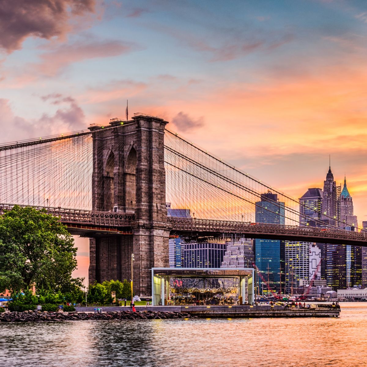 Sunset casts glow over bridge and distant city skyline.