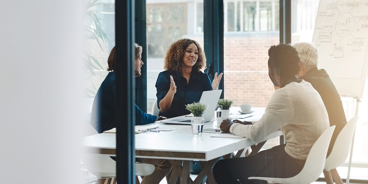 Four professionals seated around table engaged in active discussion.