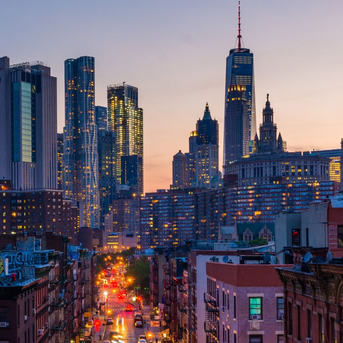 Skyscrapers glow as streetlights illuminate vibrant evening city scene.