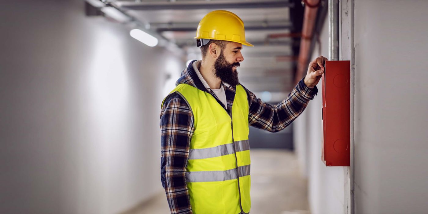 electrician standing in building in rebuilding process and checking out distribution box