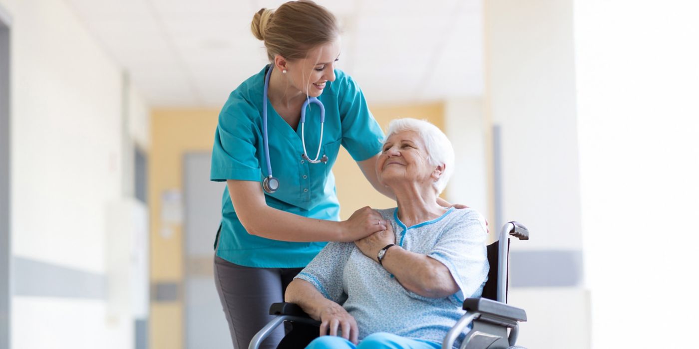 Nurse helps elderly patient seated in wheelchair with care.