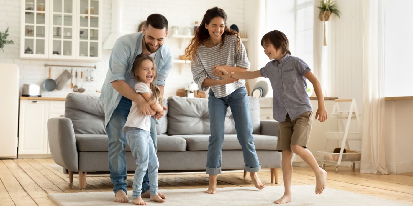 Family of four playing happily in cozy living room setting.