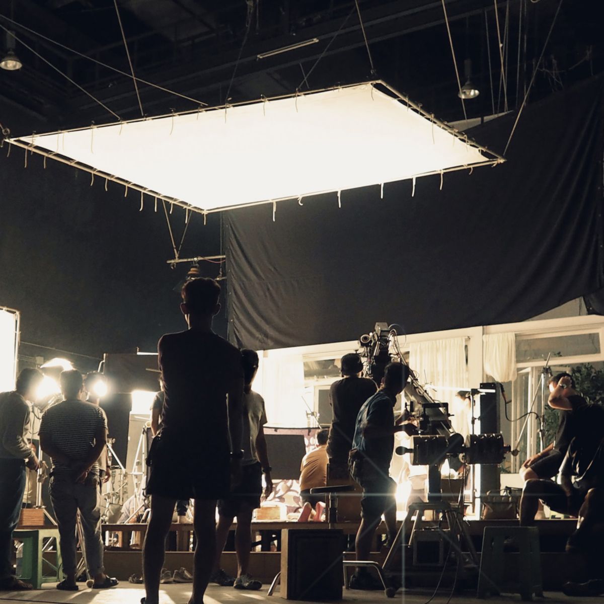 Crew members operate lighting equipment on active movie set location.