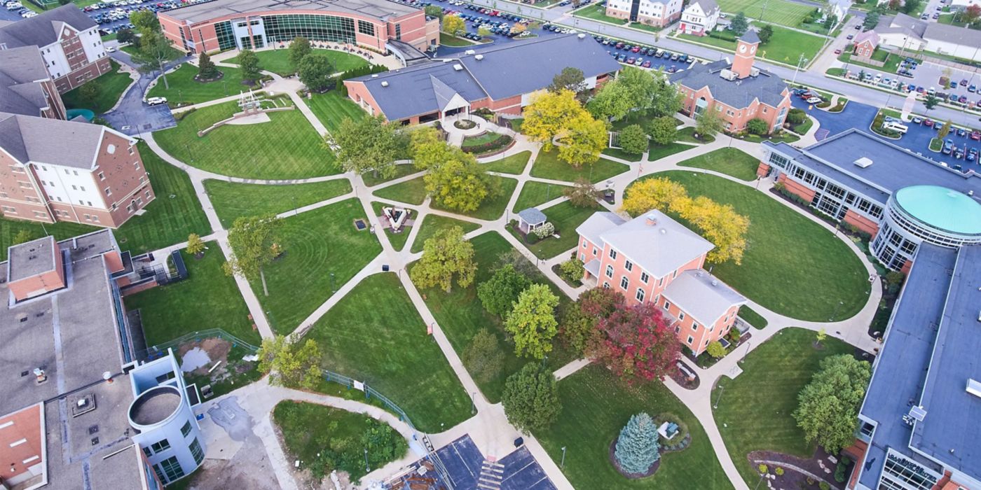Green lawns, winding paths, academic buildings under clear sky.