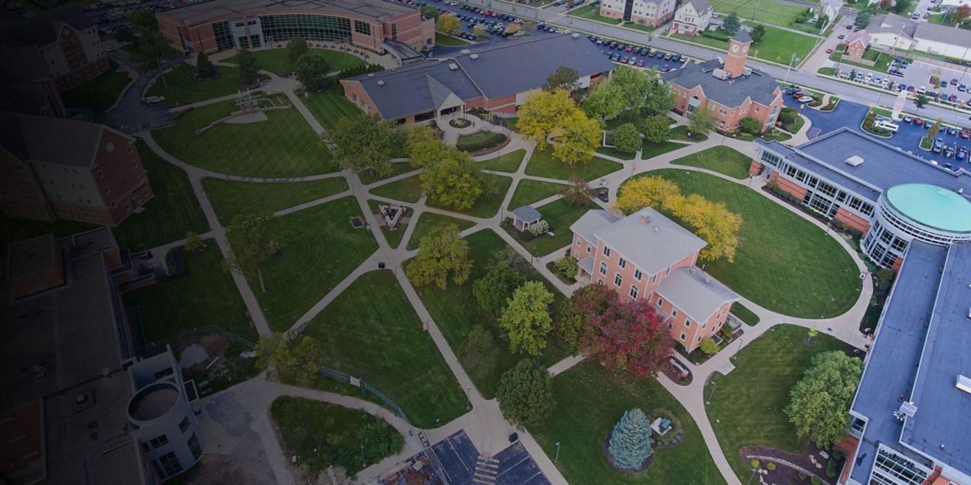 Green lawns, winding paths, academic buildings under clear sky.