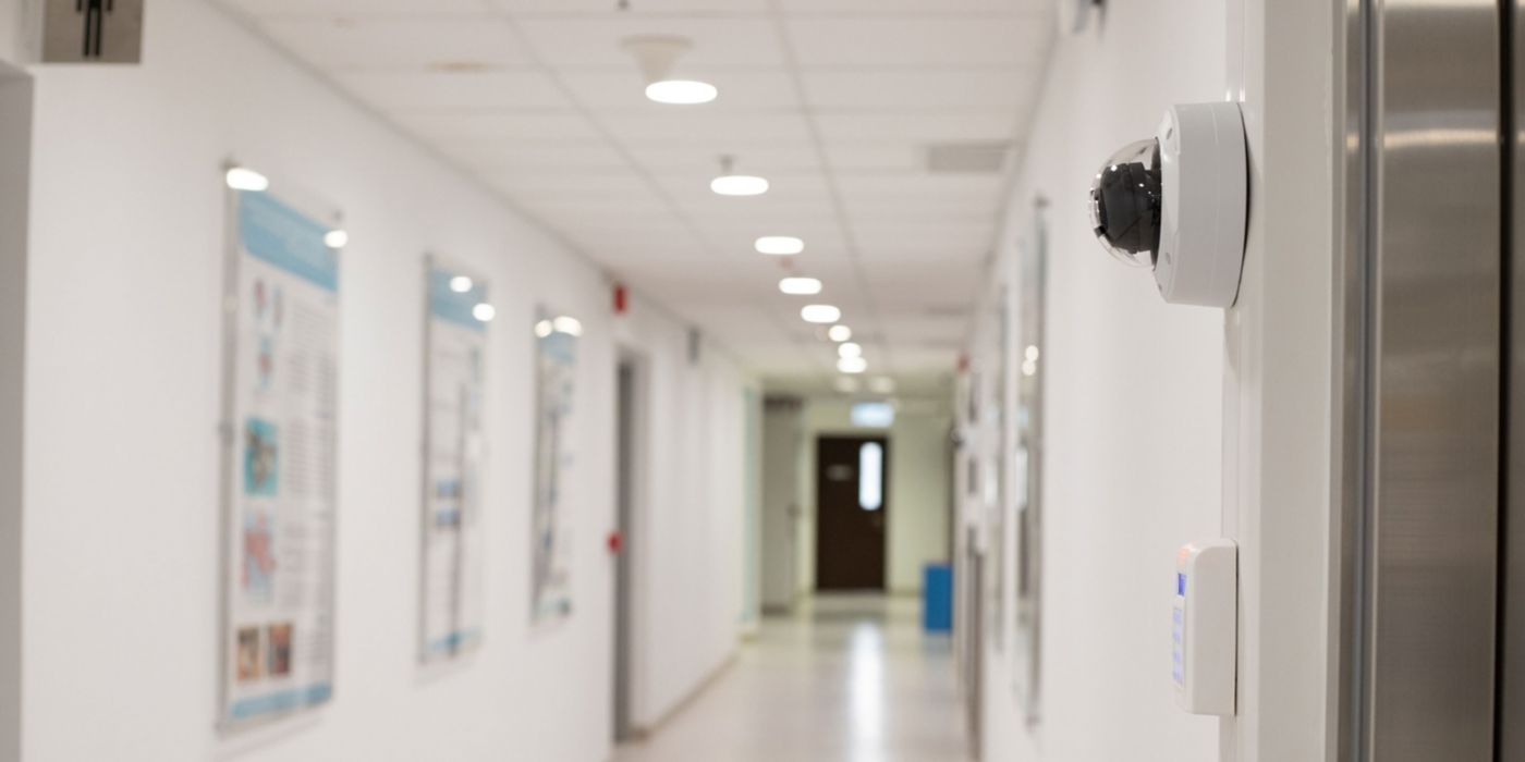 Security surveillance system (camera and digital smart door lock) at the entrance to a modern office building or advanced laboratory with blurred corridor