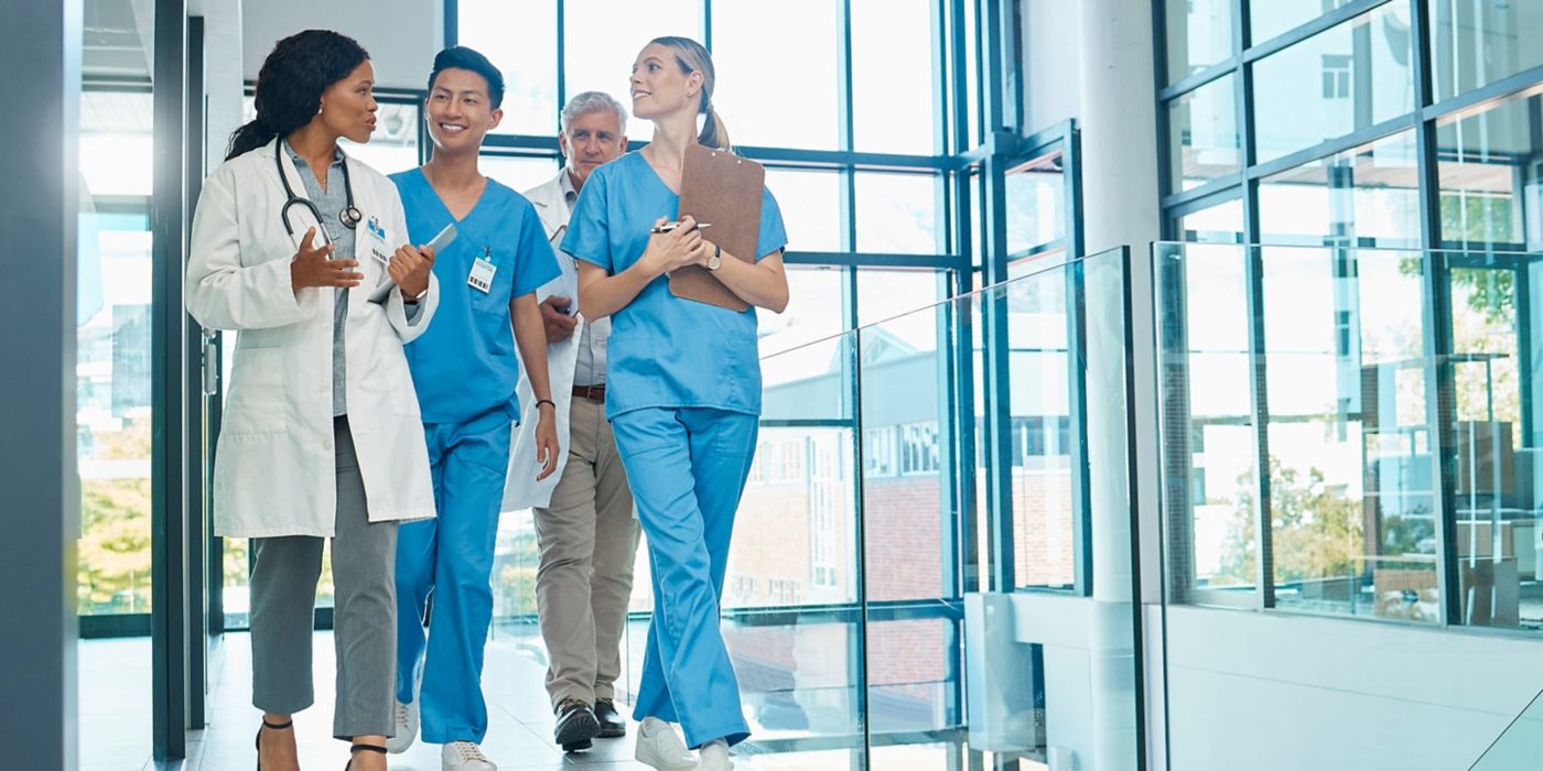 Doctors and nurses walk together in bright hospital hallway.