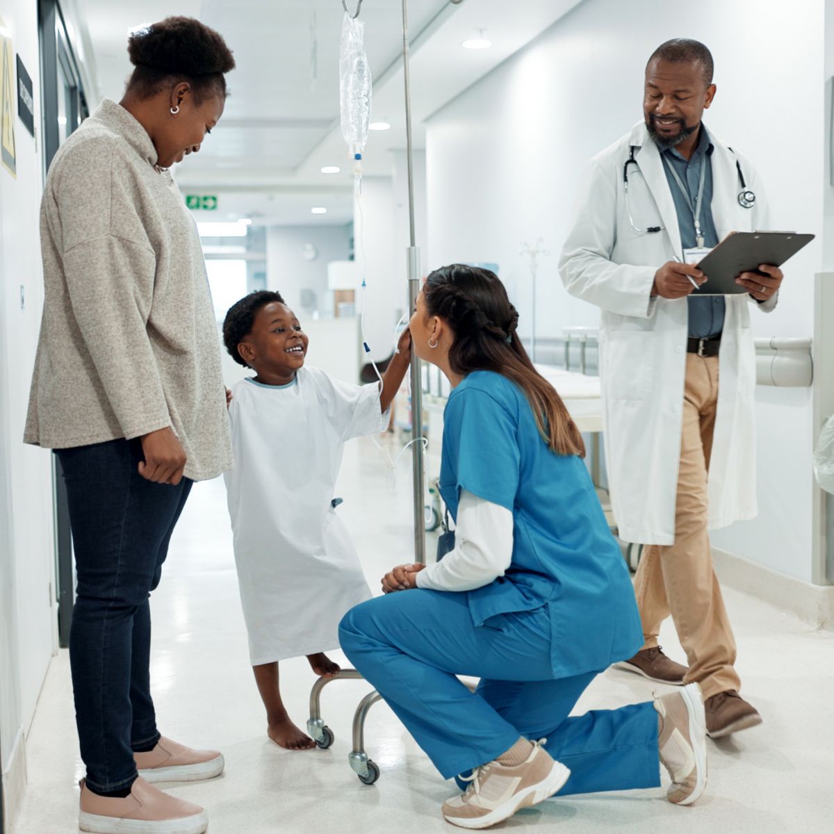 Child with doctors and guardian in bright hospital hallway setting.