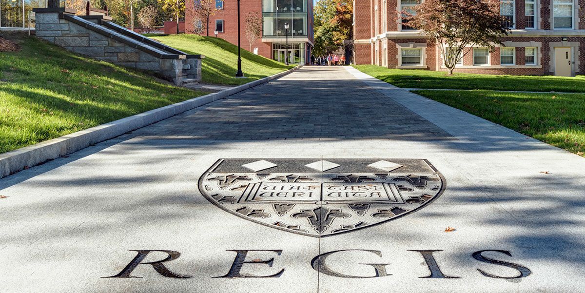 Regis College logo displayed on the ground at the entrance of the campus