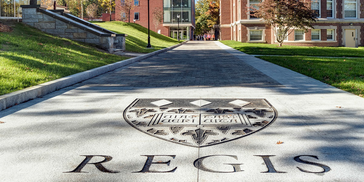 Regis College logo displayed on the ground at the entrance of the campus