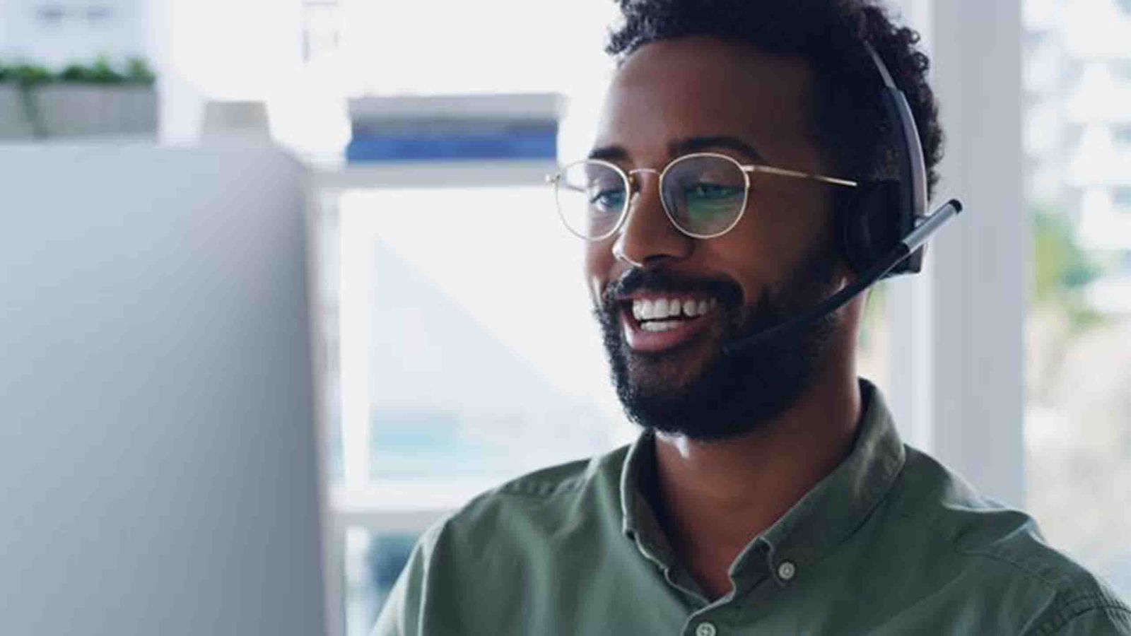 Friendly customer support agent using a headset at a desktop, delivering professional remote service and real-time customer assistance.