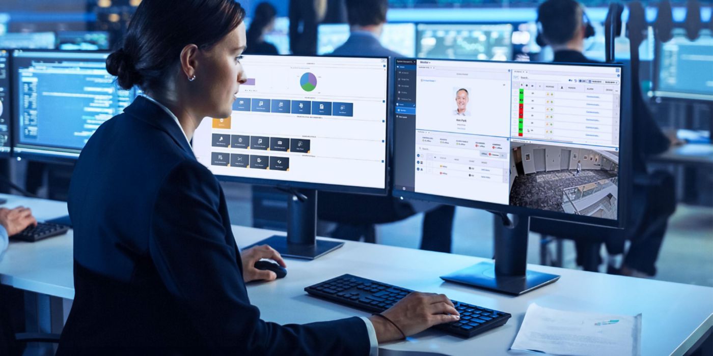 A security operations workstation displays real‑time dashboards and surveillance feeds across dual monitors in a modern control room.