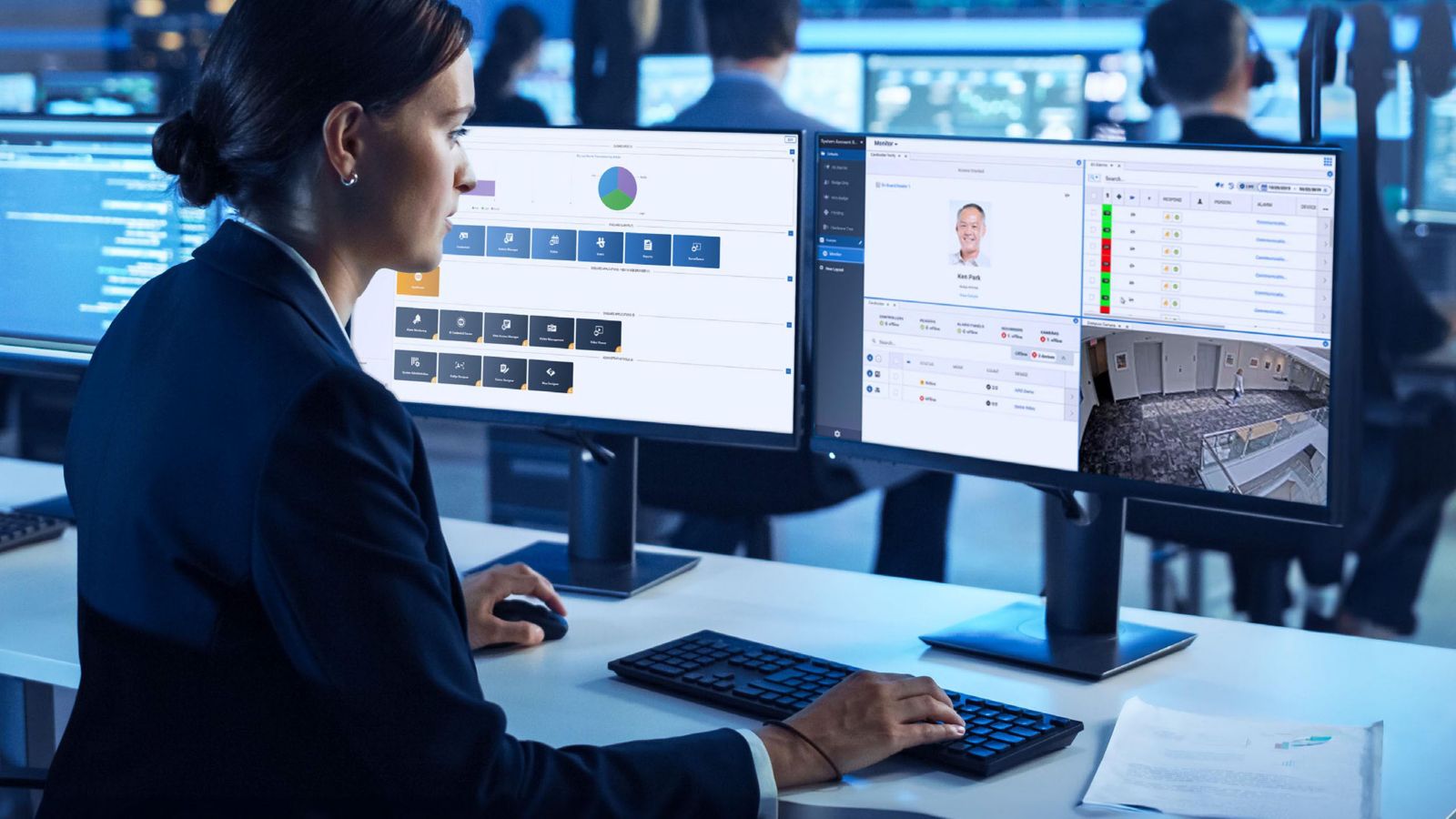 A security operations workstation displays real‑time dashboards and surveillance feeds across dual monitors in a modern control room.