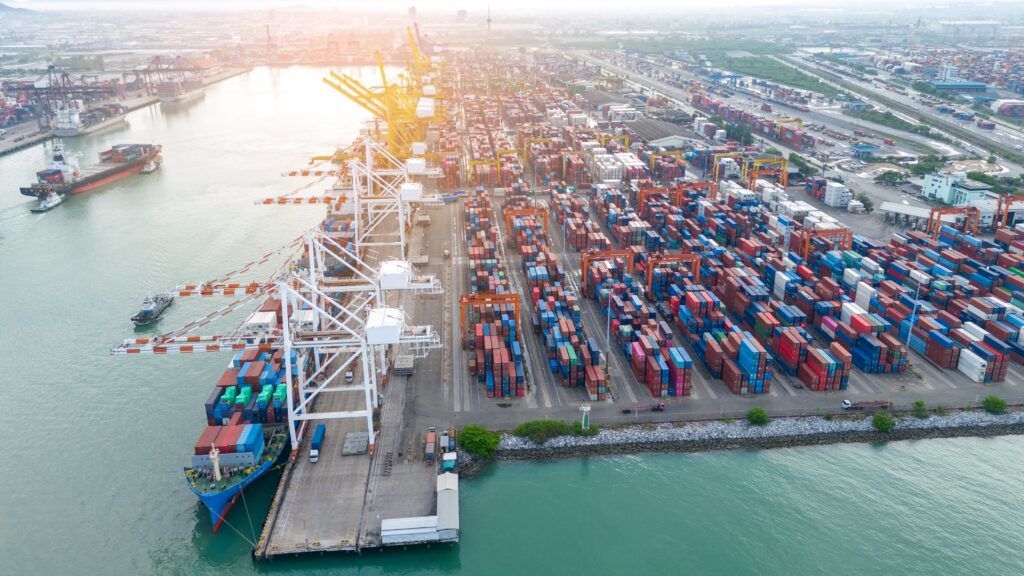 Crane loading box container to cargo ship at commercial dock port. Shipyard Cargo Container Sea Port Freight forwarding service logistics and transportation. International Shipping Depot