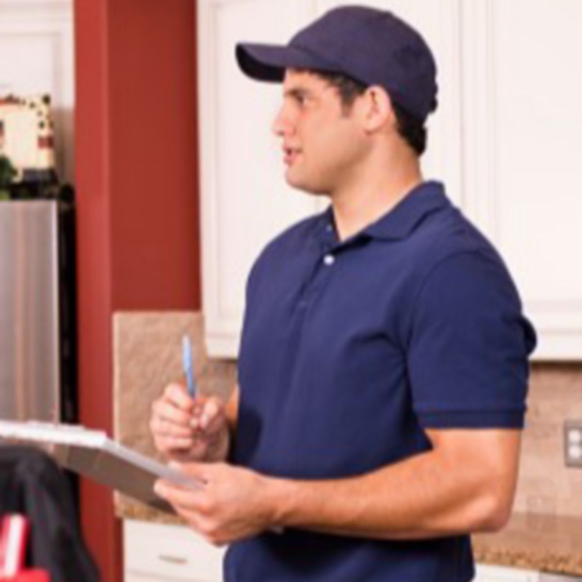 Male contractor with clipboard in kitchen