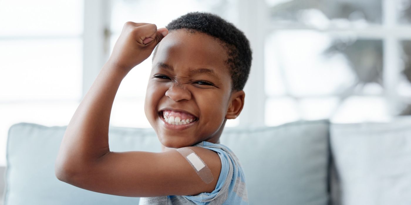Child flexes arm with bandage after receiving a vaccine.