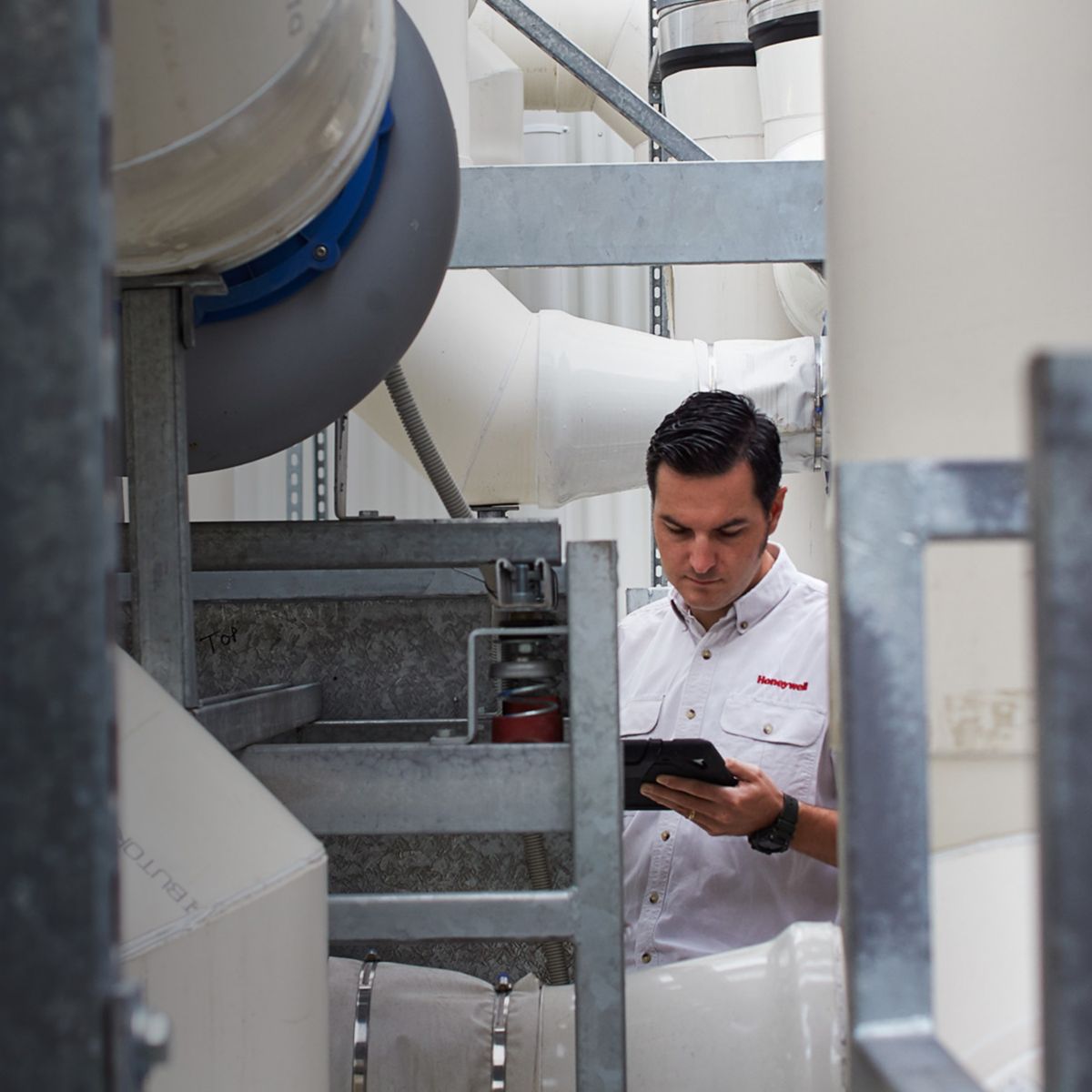 Image of an industrial maintenance technician inspecting a complex HVAC system. The technician is surrounded by large pipes and ducts, ensuring the system's efficiency and functionality. Ideal for articles on industrial maintenance, HVAC systems, and technical inspections.