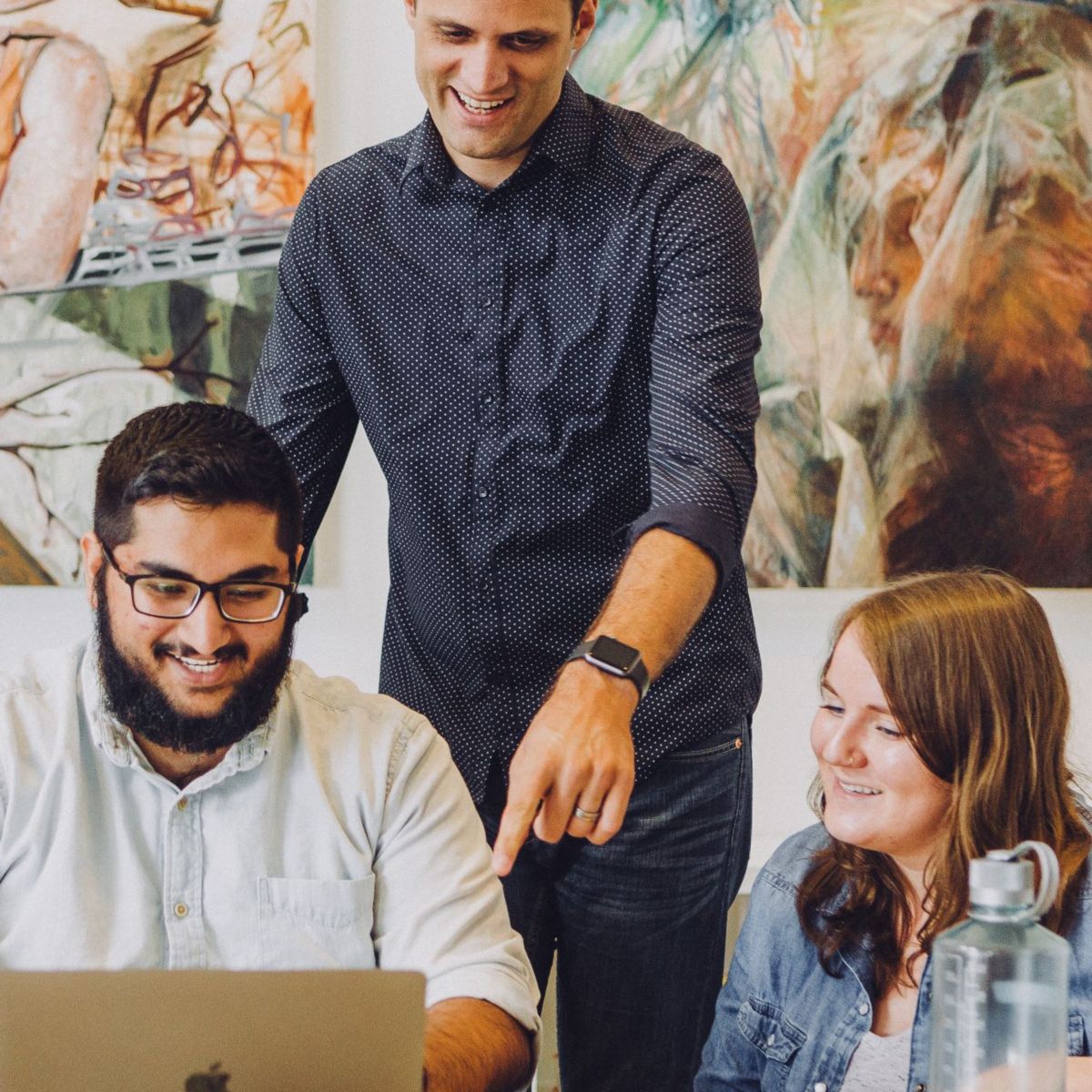 Young professionals gathered around looking at laptop
