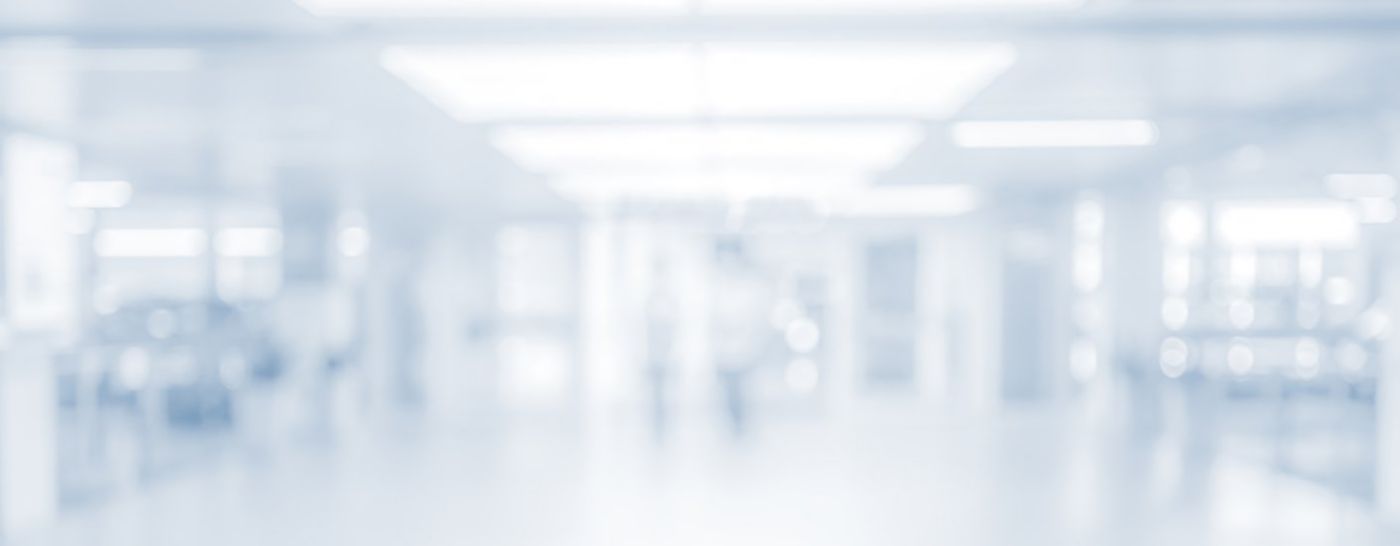 An empty hospital corridor appears softly blurred beneath bright ceiling lights.