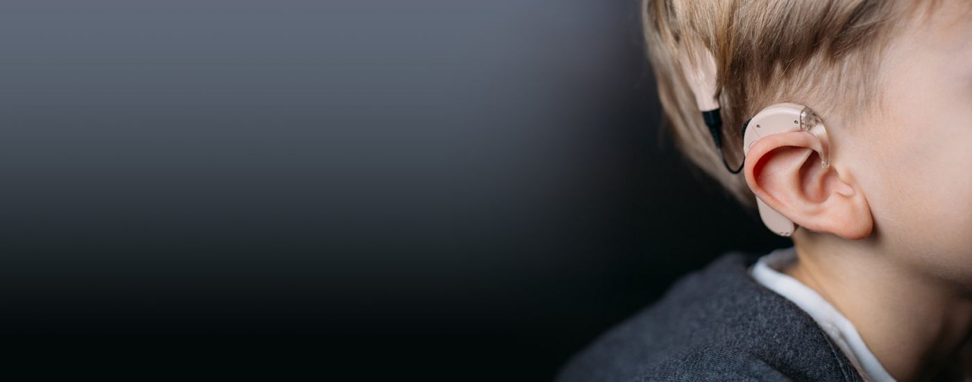 Close view of a child wearing a behind-the-ear hearing aid.
